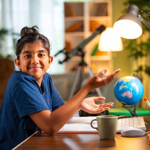 Indian asian small girl studying at home on computer desk