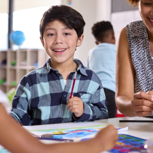 Female Teacher With Multi-Cultural Elementary School Pupils In Art Class At School