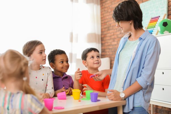 Young woman playing with little children indoors